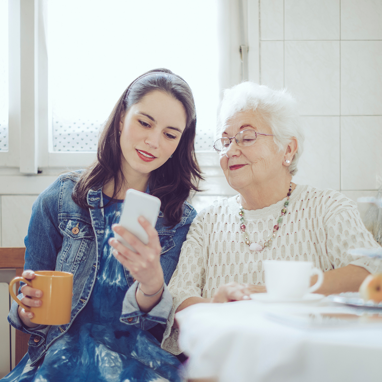 A young woman with an older women checking a cell phone.
