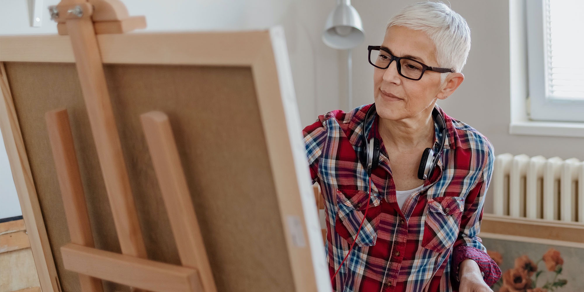 Older woman painting on a canvas.